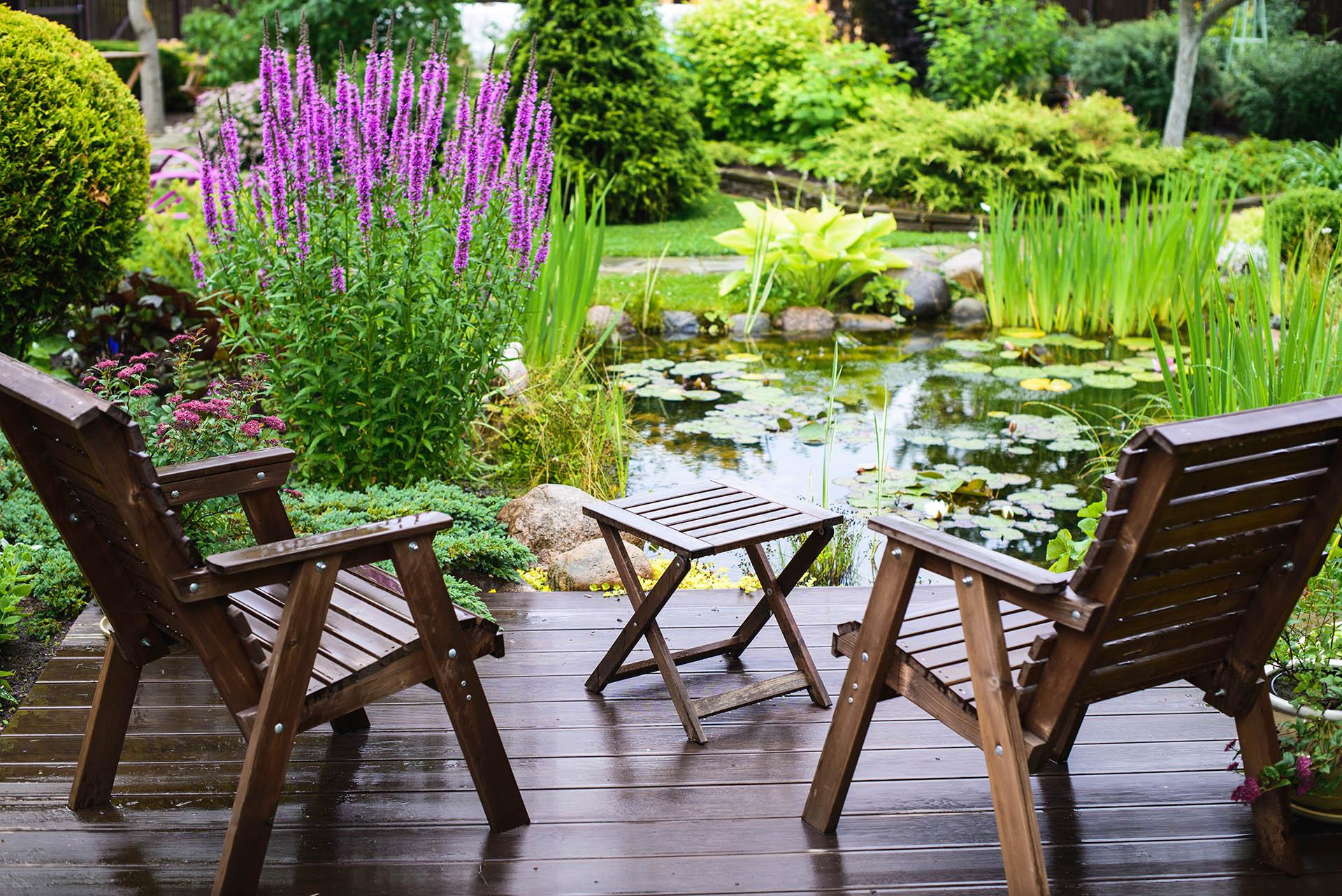 Wooden patio furniture overlooking peaceful garden pond